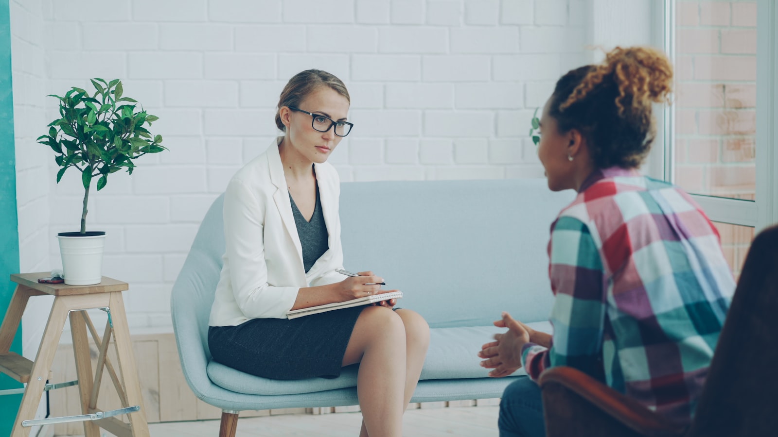 A therapist and a client sitting facing each other in a bright room